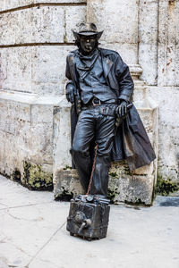 Full length of man holding umbrella standing against wall