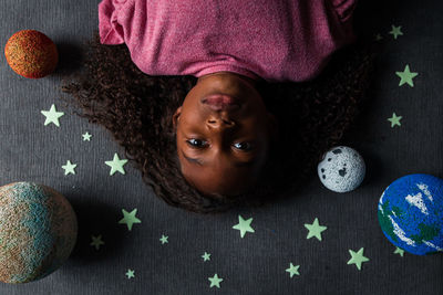 Overhead portrait of girl lying amidst solar system