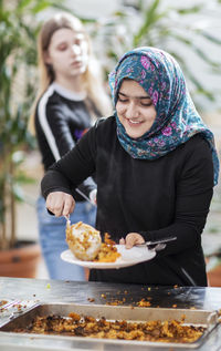 Smiling girl putting food on plate