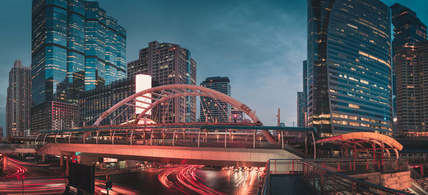 Illuminated bridge and buildings against sky at night