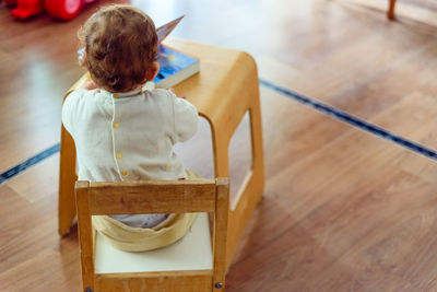 Rear view of boy sitting on table at home