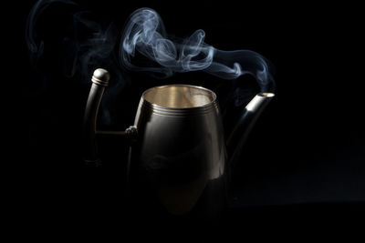 Teapot with steam on black background