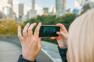 Cropped image of woman photographing through smart phone