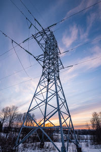 Low angle view of electricity pylon against sky during sunset