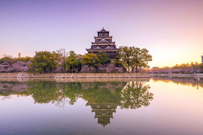 Traditional building by lake against sky