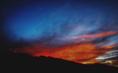 Scenic view of silhouette mountains against dramatic sky