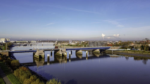 Bridge over river against blue sky in city