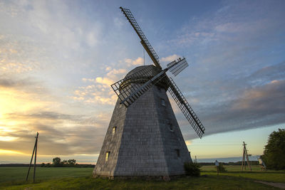 Traditional windmill on field against sky during sunset