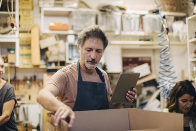 Craftsperson opening cardboard box in upholstery workshop