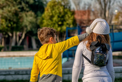 Rear view of friends with umbrella against blurred background