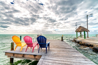 Chairs and table at beach against sky