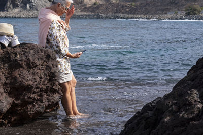 Senior woman using smart phone while standing in sea