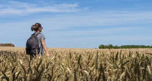 Woman with a backpack hiking through the countryside and fields