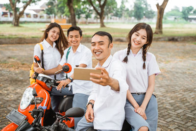 Portrait of smiling friends using mobile phone