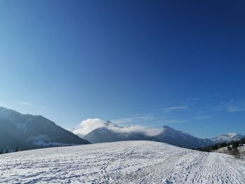 Scenic view of snowcapped mountains against blue sky