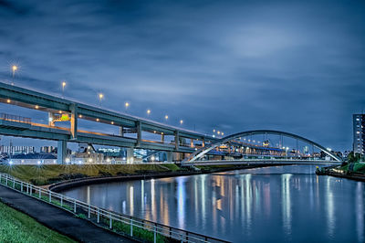 Illuminated bridge over river against sky at night