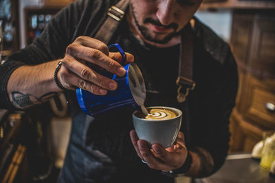 Midsection of man holding coffee at cafe