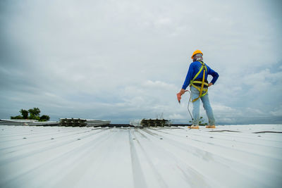 Asian construction workers are installing metal roofing sheets for industrial roof installations.