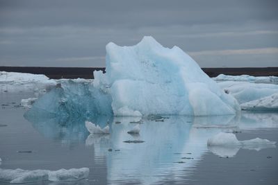 Scenic view of glaciers on lagoon against cloudy sky