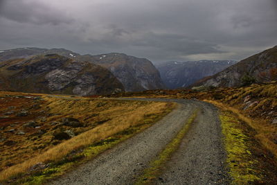 Road leading towards mountains against sky