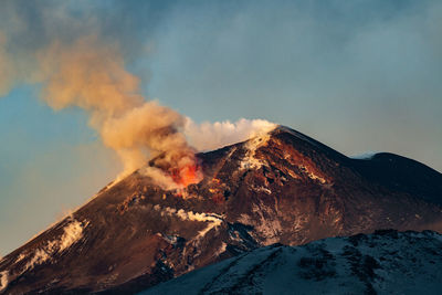 Smoke emitting from volcanic mountain against sky
