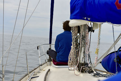 Rear view of men sailing on sea against sky