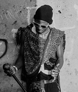 Young man wearing sunglasses standing against wall