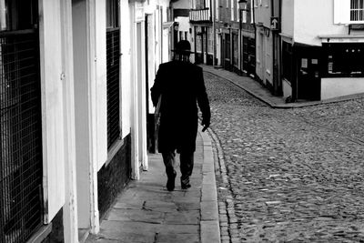 Rear view of woman walking on footpath in city