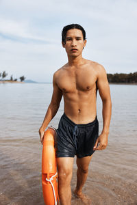 Portrait of shirtless man standing at beach