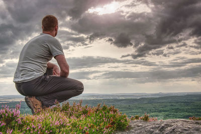 Man sitting on hill summit. conceptual scene. he wearing light outdoor clothes. he looking forward