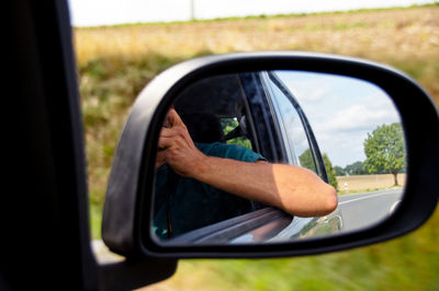 Reflection of man in side-view mirror of car