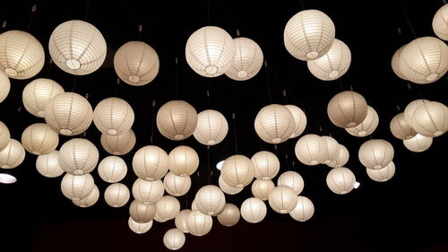 Low angle view of illuminated lanterns hanging against black background