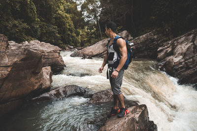 Side view of man surfing on rock at waterfall