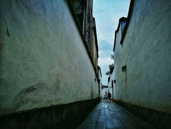 Rear view of people walking in alley amidst buildings