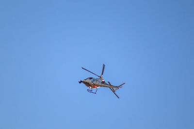 Low angle view of helicopter flying against clear blue sky