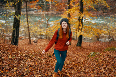 Portrait of beautiful woman standing in forest during autumn