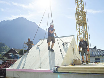 Carpenters installing roof with crane on sunny day