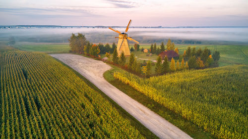 Traditional wooden windmill morning landscape. rural sunrise, foggy green fields. dudutki village