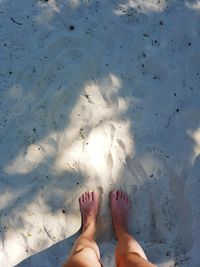 Low section of woman standing on sand