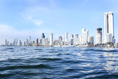 Sea and cityscape against blue sky