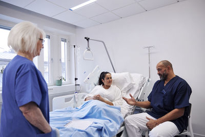 Female patient on hospital bed talking to nurse