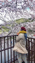 Rear view of woman standing by cherry tree in winter