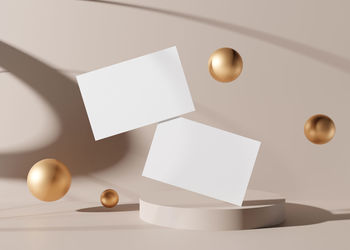 Blank white business cards with golden spheres on cream background. mock up for branding identity
