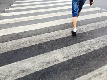 Low section of person walking on zebra crossing