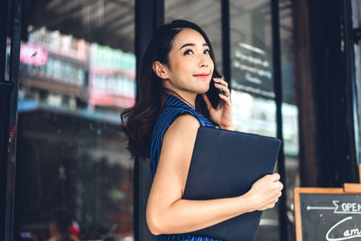 Young woman looking away while standing on glass