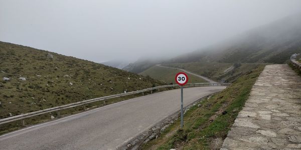 Road sign on mountain against sky