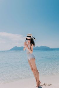 Woman standing on tiptoe at beach against sky