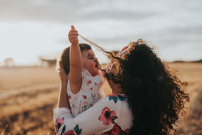 Woman holding baby girl on landscape