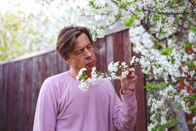 Mature man looking at flowering plant in park during spring