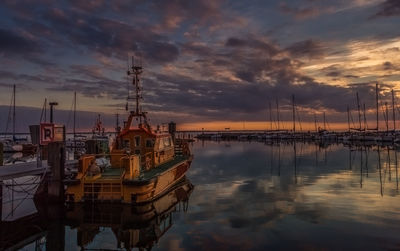 Sailboats moored on sea against sky during sunset